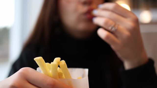 Smiling young woman enjoys french fries at a fast food restaurant creating a relatable lifestyle scene focused on casual dining and everyday moments