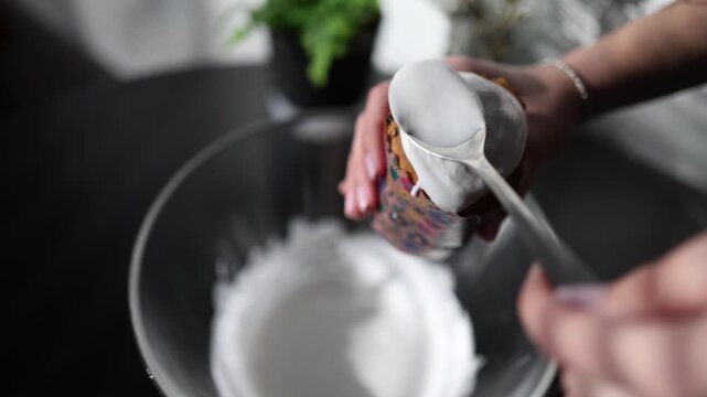 Close up baking scene with female hands spreading white icing across traditional easter bread creating festive holiday pastry in a home kitchen