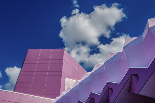 Sarasota, FL, US-May 30, 2022: Abstract view of the Van Wezel Performing Arts Center which is a pastel purple against a brilliant blue sky with puffy clouds.