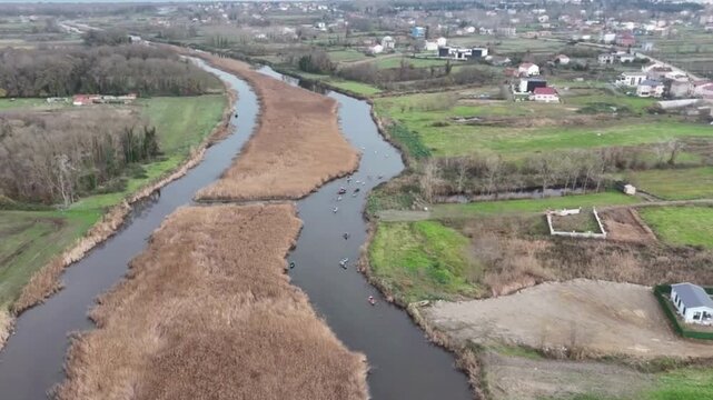 Aerial view of people in kayaks paddling through the Kizilirmak Delta surrounded by reeds and green fields in Bafra, Samsun, Turkiye.
