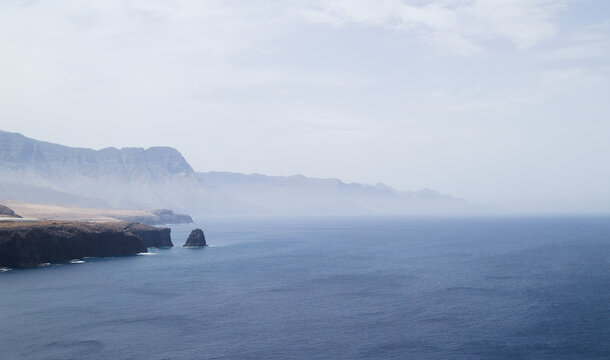 Distant View of Risco Faneque Cliff and the Cola de Dragon Mountain Formations with the Roque Partido Sea Stack on the Coastline of Gran Canaria
