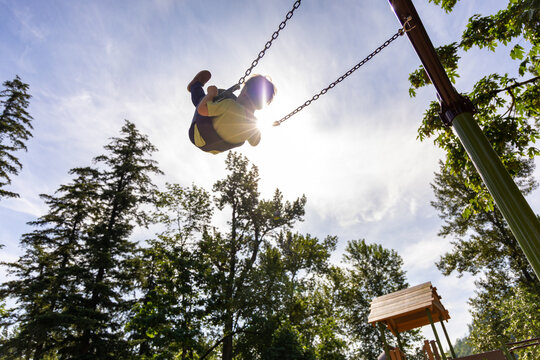 Child Swinging High at Peach Park in Chilliwack, British Columbia, Canada on a Sunny Day