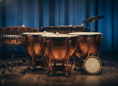 Close-up of a percussion ensemble with timpani, snare drum, and cymbals on stage