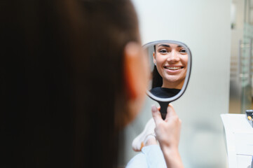 Patient smiling seeing braces in mirror at dental clinic