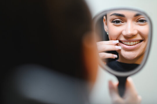 Young woman client proudly checking braces in mirror