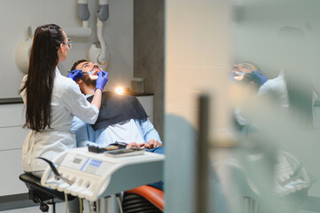 Naklejka premium Dentist examining patient's teeth in clinic