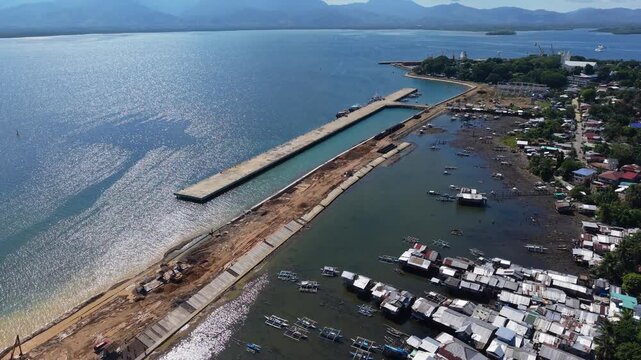 Wide aerial view of Puerto Princesa port expansion in Palawan with reclaimed land concrete pier work and shoreline community
