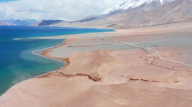 Forward flight tilting up from blue water to snow peaks at Pangong Lake.. High Altitude Lake in Greater Himalayas