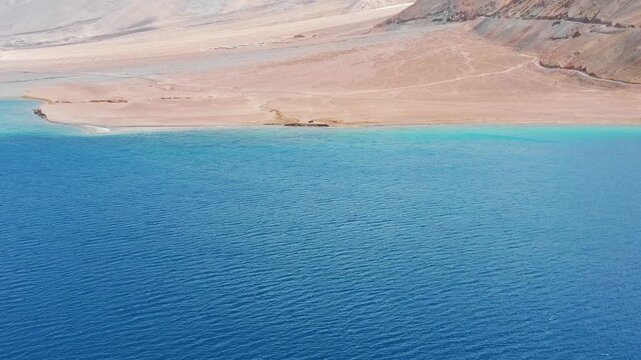 Forward flight tilting up from blue water to snow peaks at Pangong Lake.. High Altitude Lake in Greater Himalayas