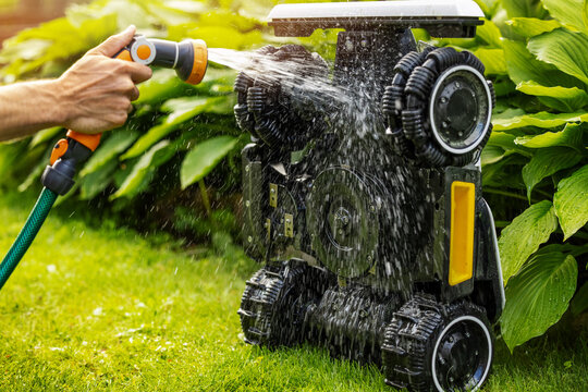 Cleaning robotic lawn mower. Washing with water from garden hose