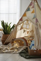 Cute wigwam with fairy lights and toys in stylish child's room © New Africa