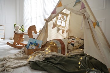 Cute wigwam with fairy lights and toys in stylish child's room © New Africa