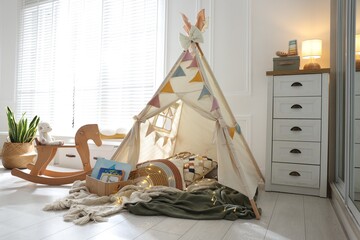 Cute wigwam with fairy lights and toys in stylish child's room © New Africa
