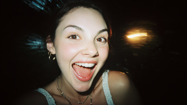 Candid retro style photo of a playful woman smiling and laughing in disposable camera flash
