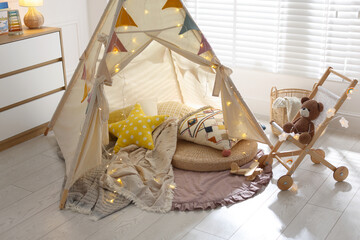 Cute wigwam with fairy lights and toys in stylish child's room © New Africa