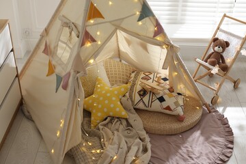 Cute wigwam with fairy lights and toys in stylish child's room, above view © New Africa
