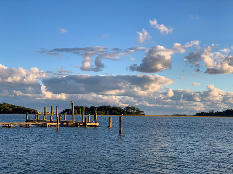 A quiet dock extends into calm coastal waters beneath dramatic evening clouds in Swansboro, North Carolina, capturing the peaceful atmosphere of the coast.