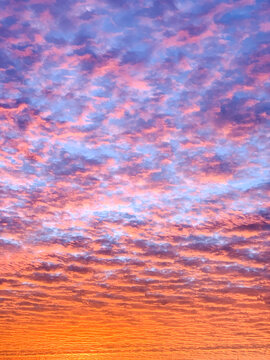 Brilliant shades of orange, pink, and purple illuminate textured clouds at sunrise over North Carolina&rsquo;s Outer Banks, creating a dramatic coastal sky.