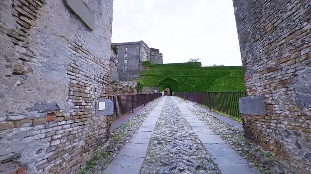 POV walking through the large iron gates into the historic Priamar Fortress in Savona, Italy