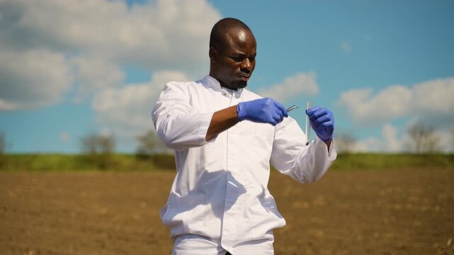 African American agronomist analyzing soil sample in test tube
