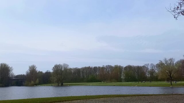 Scenic landscape of Rheinaue Freizeitpark in Bonn Germany, wide view of a lake and green meadow under cloudy sky