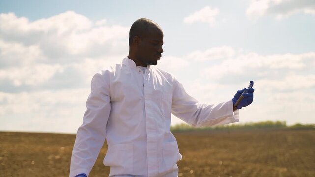 African American agronomist scientist performing soil test analysis in a field
