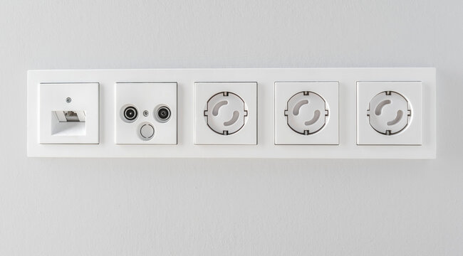 Row of White Electrical Outlets and Media Sockets Mounted on a Clean Modern Wall