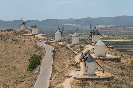 Scenic aerial view of the historic white windmills of Consuegra in La Mancha, Spain. Traditional Spanish landmarks on a dry hill along a rural road in summer.