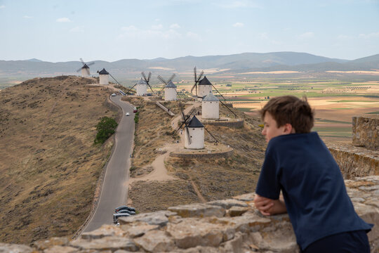 Young traveler enjoying the panoramic view of the iconic windmills of Consuegra, Spain. Historic landmark of La Mancha and one of the most famous Don Quixote destinations.