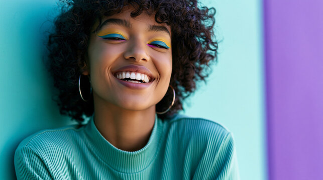 Close-up of a joyful woman with curly hair and bold colorful eye makeup flashing a bright smile against a two-tone background, bold beauty concept, vibrant portrait photography,