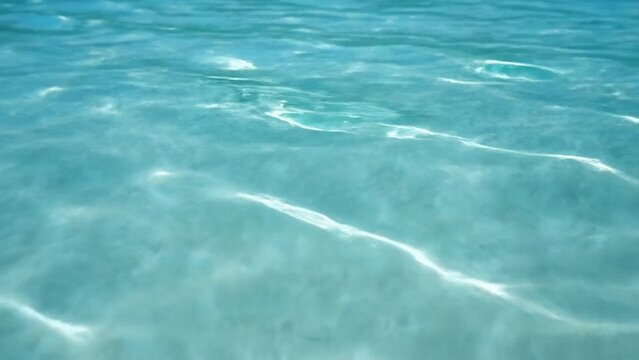 Clear turquoise seawater with sunlit ripples and soft caustic patterns, calm minimal ocean texture for serene summer mood, ideal as abstract background