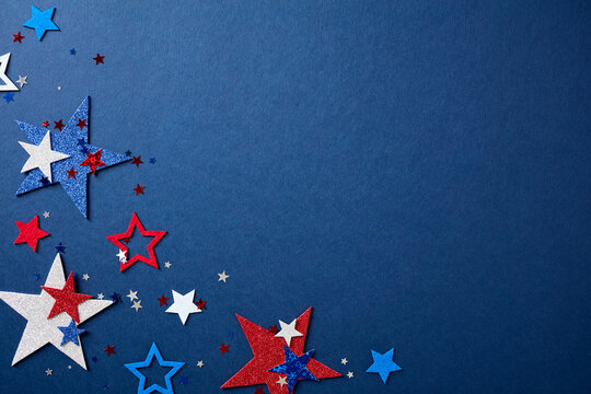 Festive border made of red, white, and blue stars on the left side over a textured navy blue background. Patriotic flat lay with copy space for 4th of July design