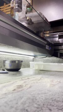 Pizza chef stretching dough on floured countertop