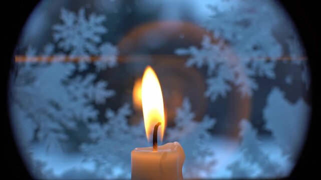 Close up of burning candle flame against frosted winter window pane with blue ice crystallization