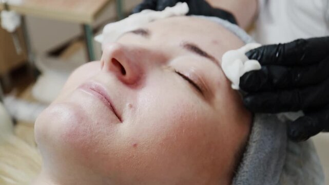 A female doctor, a professional cosmetologist, prepares a patient's face for a procedure