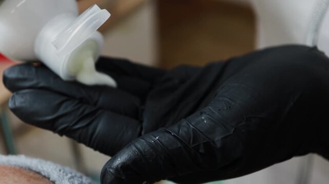 A female doctor, a professional cosmetologist, applies facial ointment to her gloves