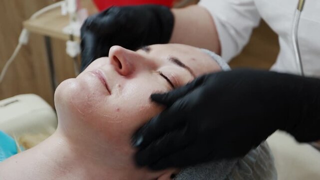 A female doctor, a professional cosmetologist, prepares a patient's face for a procedure