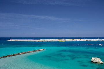 Fototapeta premium Harbour wall \harbor wall in Puglia southern italy with single yacht turquoise sea and blue sky in summer