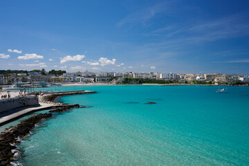 Fototapeta premium Harbour and coast of Otranto, Italy with single yacht turquoise sea and blue sky in summer