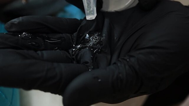 A female doctor, a professional cosmetologist, applies facial ointment to her gloves