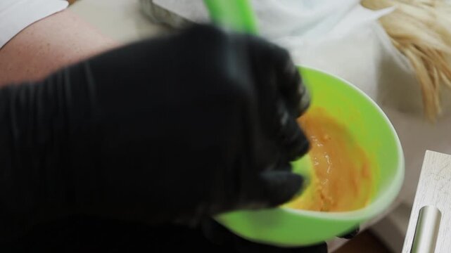 A female doctor, a professional cosmetologist, mixes a mask for application to a patient's face