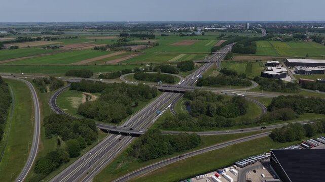 Aerial view of a highway interchange with cloverleaf ramps surrounded by green fields and trees in Utrecht, Utrecht, Netherlands.