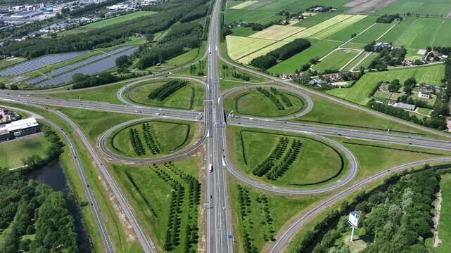 Aerial view of the Knooppunt Heerenveen cloverleaf interchange with surrounding green fields and industrial areas in Heerenveen, Friesland, Netherlands.