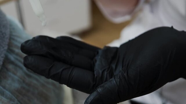 A female doctor, a professional cosmetologist, applies facial ointment to her gloves