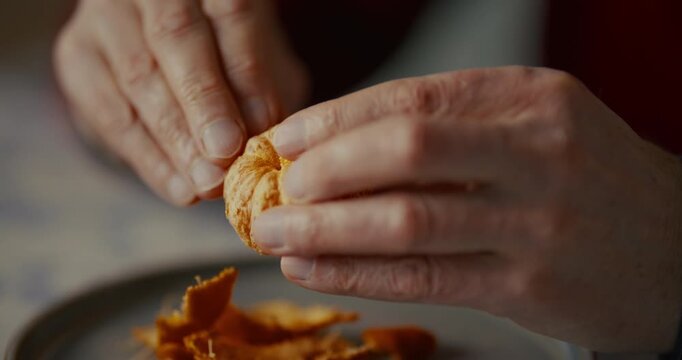 Hands handling a small piece of food over a plate in soft indoor light