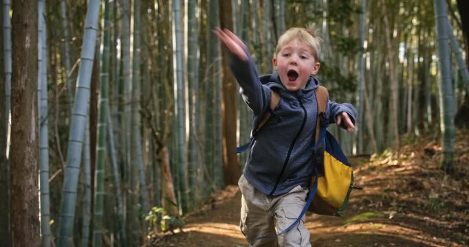 Silly little boy playing and running off on bamboo grove path - steady cam shot