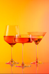 Fototapeta premium Colorful Assorted Cocktail Glasses on Vibrant Yellow and Pink Gradient Background