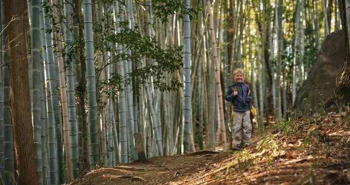 Child with backpack posing for camera in bamboo grove then walking down dirt path