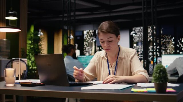 Stressed businesswoman ripping paper after noticing mistake and typo, sitting at office desk late at night. Overwhelmed employee shows frustration and disappointment over poor results.
