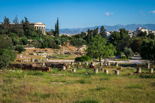 Scenic view of the Ancient Agora in Athens with the Temple of Hephaestus overlooking the historic ruins and distant mountains beyond the city skyline.